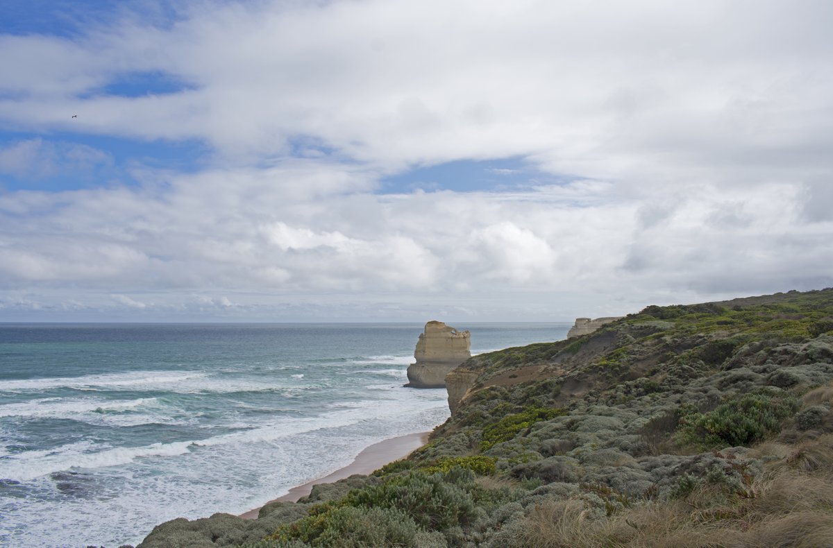 A towering limestone stack rising from the beach at the foot of the cliffs at Gibson Steps under a dramatic sky