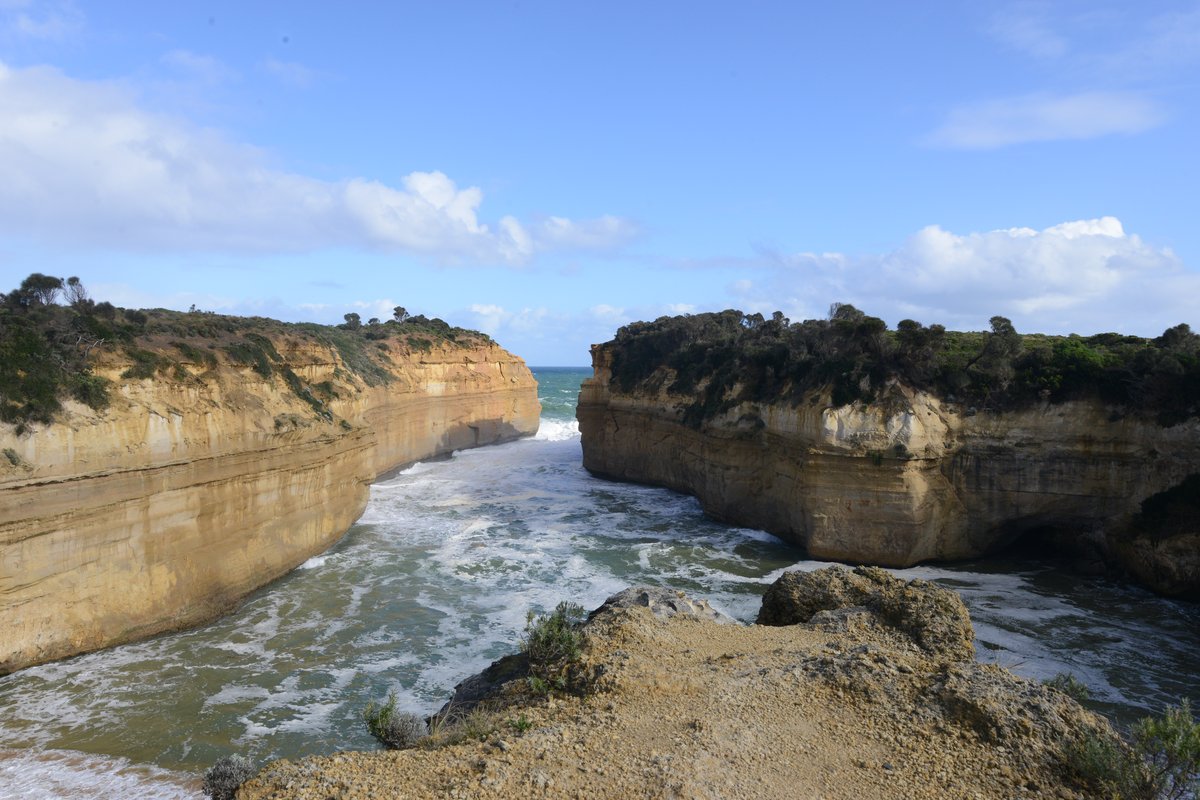 The narrow Loch Ard Gorge with sheer limestone walls channelling turquoise surf onto a hidden beach