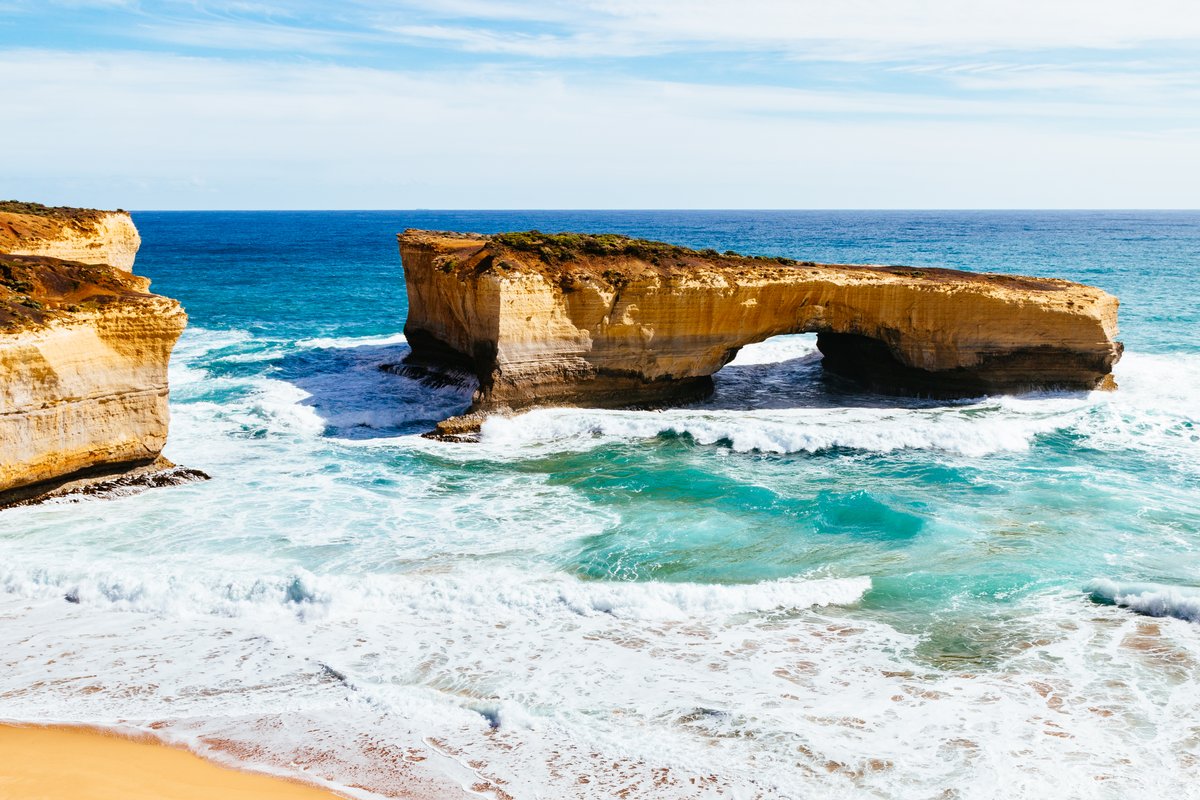 London Arch, an offshore double-span limestone formation surrounded by turquoise surf under a bright sky