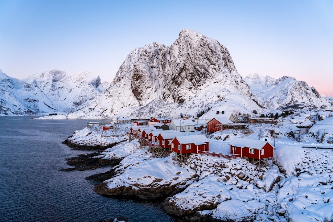 Snow-covered red rorbuer cabins at Hamnøy at twilight, Lofoten winter