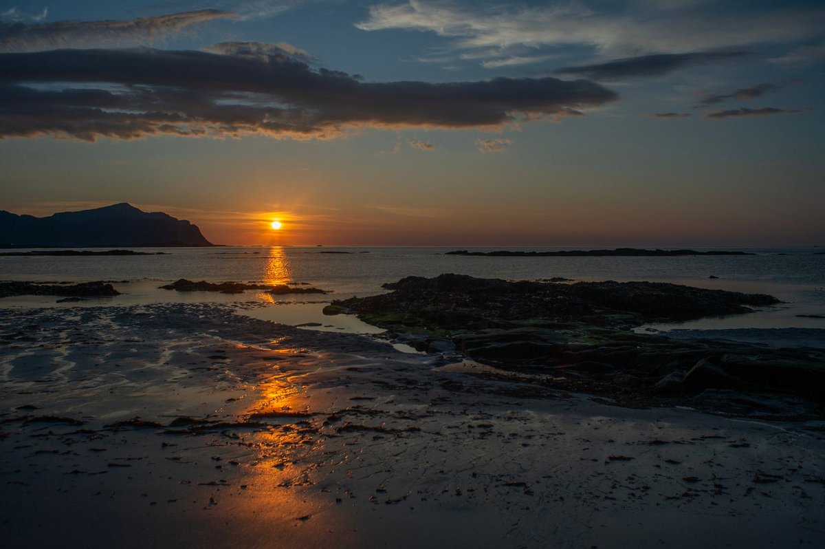 Low golden sun skimming the horizon over a Lofoten beach, northern Norway