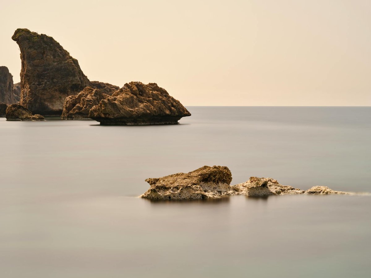 Long exposure seascape with misty smooth water flowing around coastal rocks