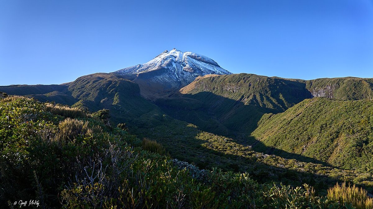 Mount Taranaki's snow-dusted cone seen from the tussock of the Pouākai Range